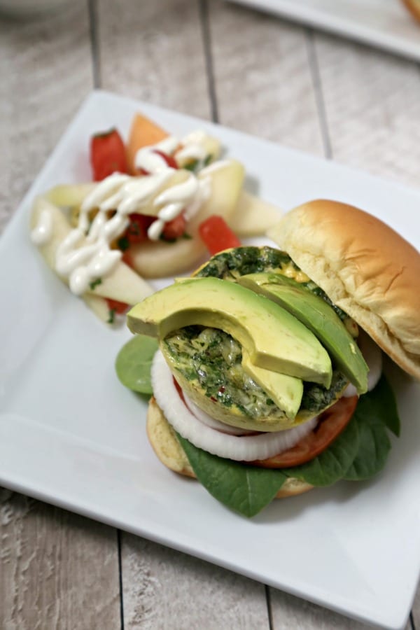 This Cheesy Breakfast Burger from CookingInStilettos.com is soon to be your favorite brunch recipe. A light as a feather quiche “burger” is nestled among fresh veggies in a pillowy bun for the perfect bite. | @CookInStilettos