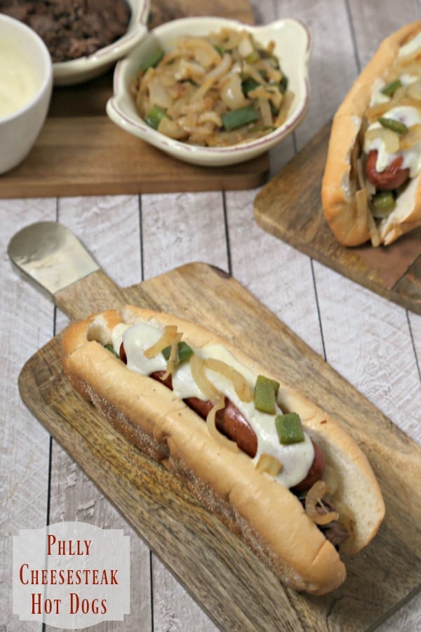 Philly Cheesesteak Hot Dogs from CookingInStilettos.com bring the flavors of the classic Philly Cheesesteak to your favorite hot dog. Griddled onions and peppers are nestled in soft Amoroso buns along with London Broil, toasty hot dogs and drizzled with a creamy provolone cheese sauce. | Philly Cheese Steak | Cheesesteak Hot Dogs | Philly Classics | Provolone Cheese Sauce | Cheesesteak Inspired Recipes